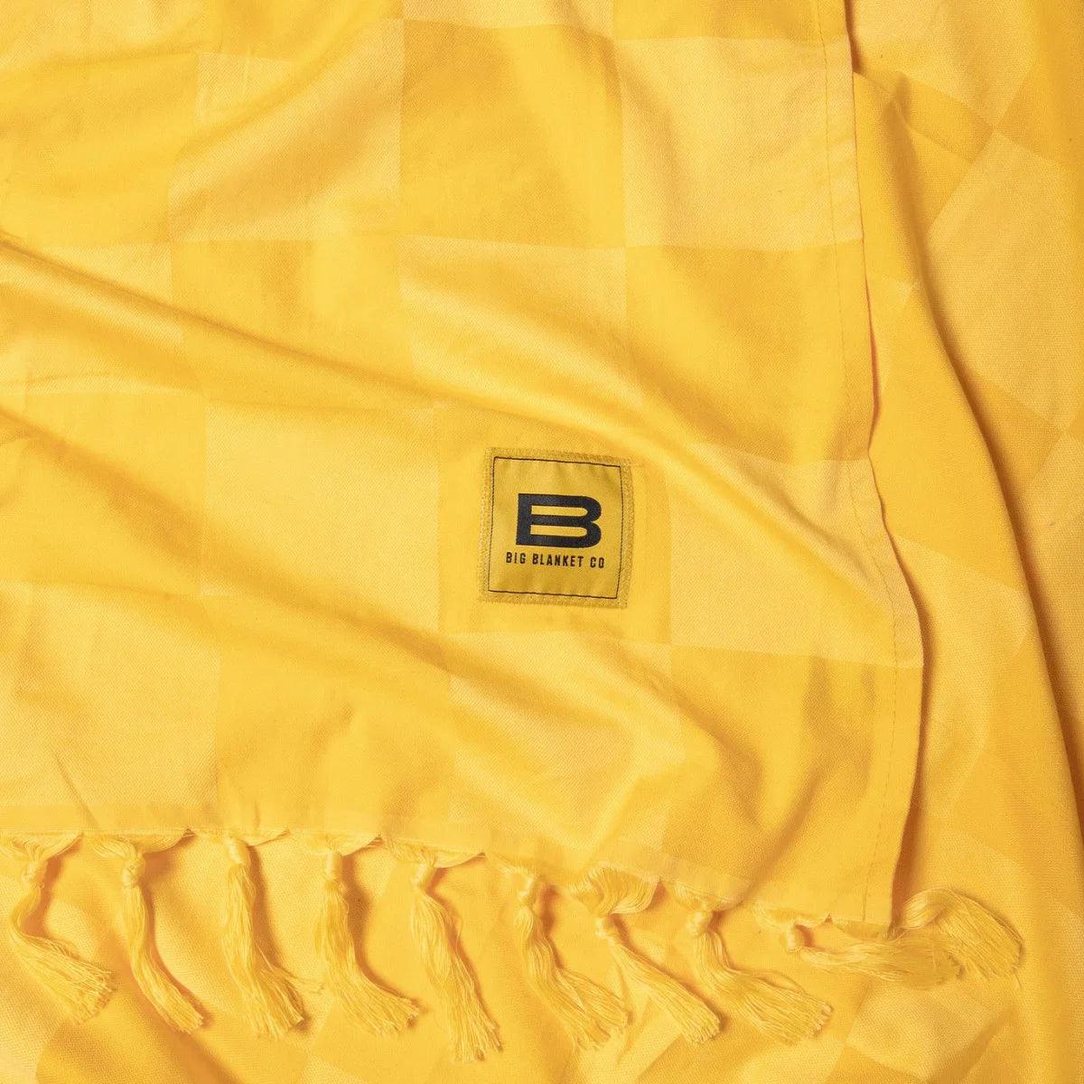 Golden yellow oversized blanket with fringe edge and Big Blanket Co logo tag