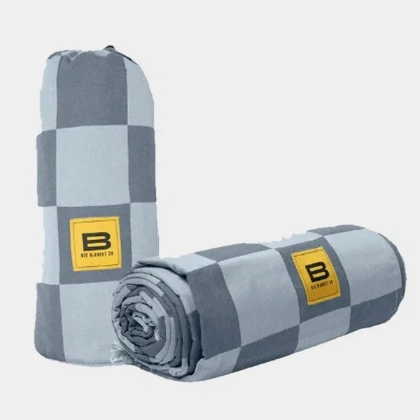 Gray and light blue checkered oversized blanket rolled and standing upright with Big Blanket Co logo patch