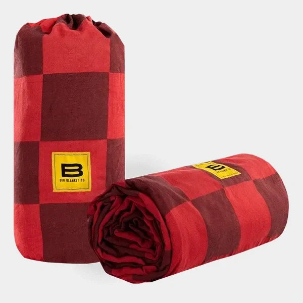 Red and burgundy checkered oversized blanket rolled and bundled with yellow Big Blanket Co logo patch