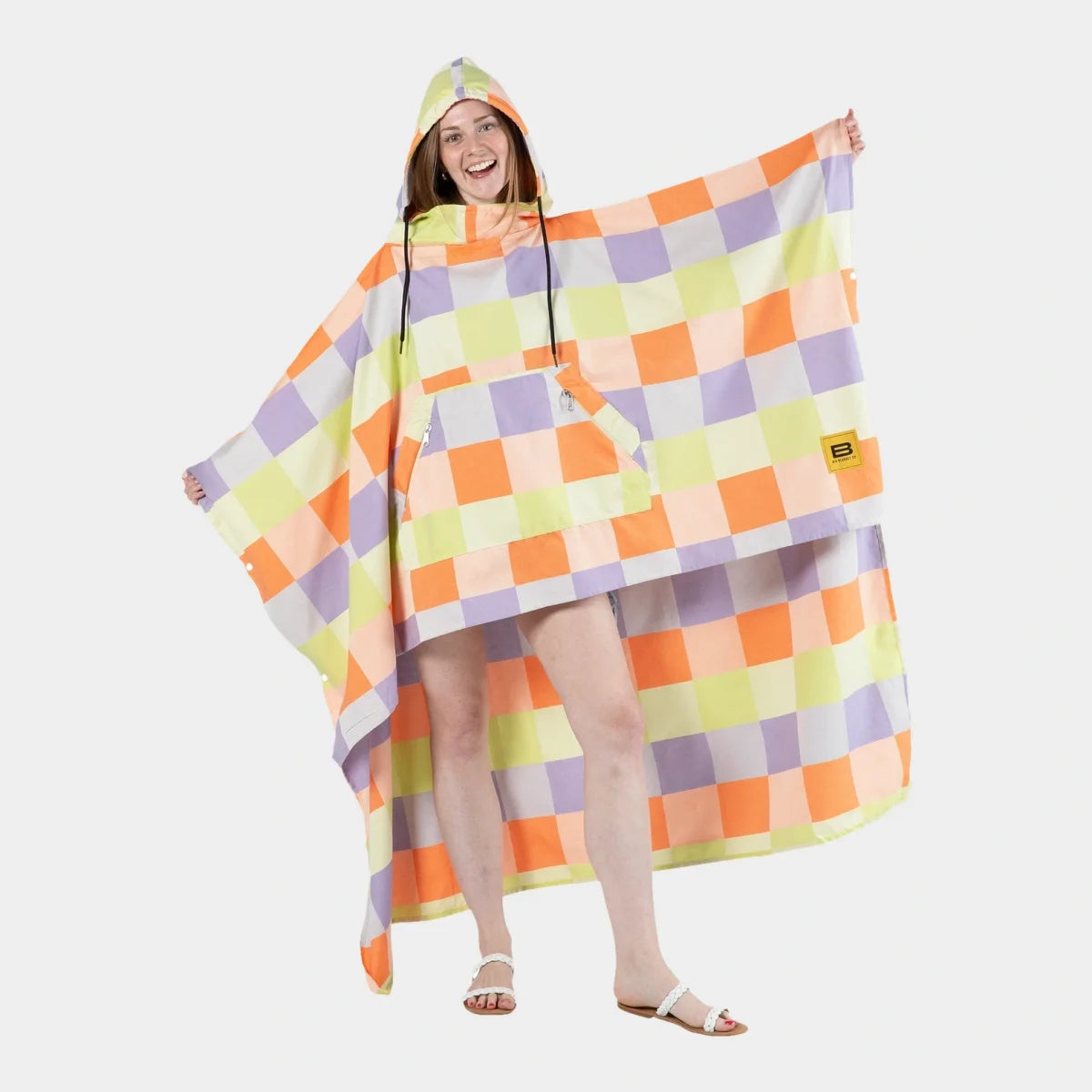 Woman wearing colorful checkerboard poncho blanket with hood in orange, yellow, purple, and white squares