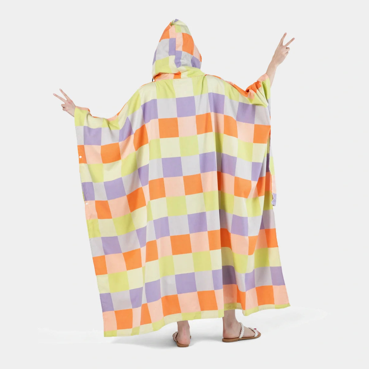 Adult wearing colorful checkerboard poncho blanket in lime, purple, orange, and cream with hood