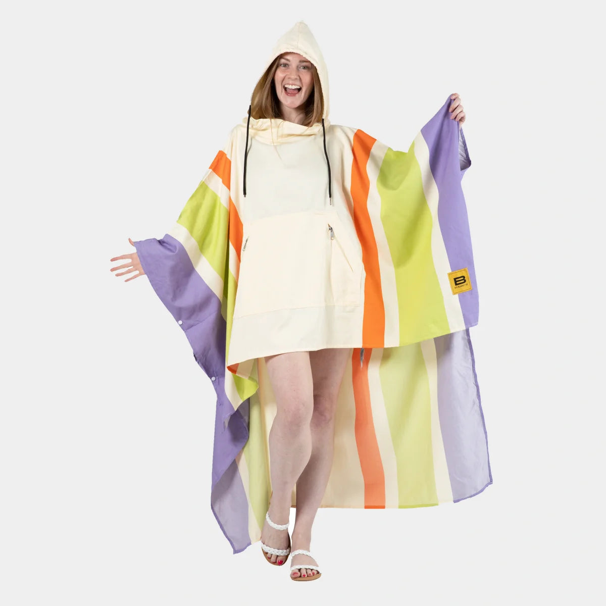 Woman wearing cream hooded poncho blanket with purple, lime, and orange vertical stripes, draped oversized