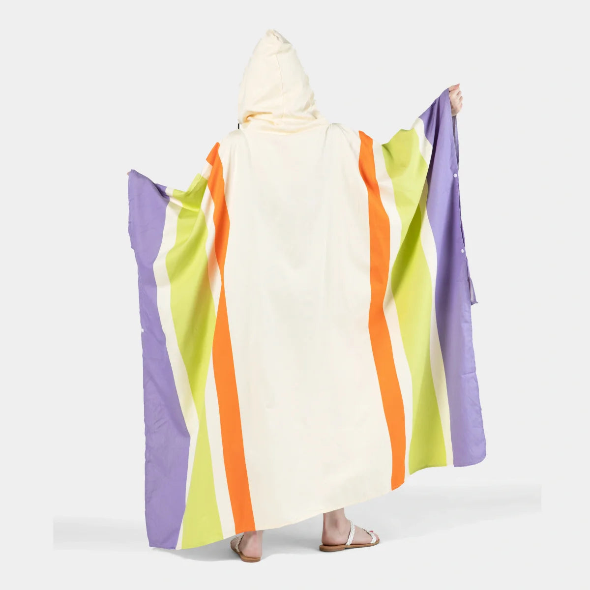 Adult wearing cream and bright striped oversized poncho blanket with purple, lime, and orange vertical stripes and attached hood