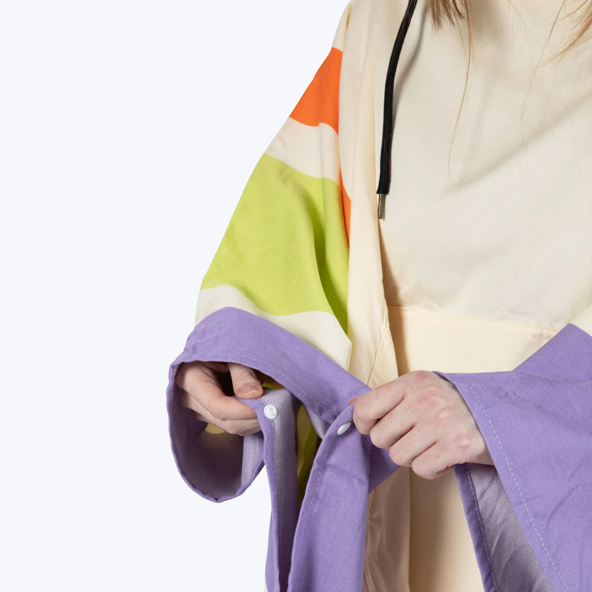 Adult wearing Big Beachy Poncho in cream with bright orange, lime green, and purple stripes, showing snap closure detail