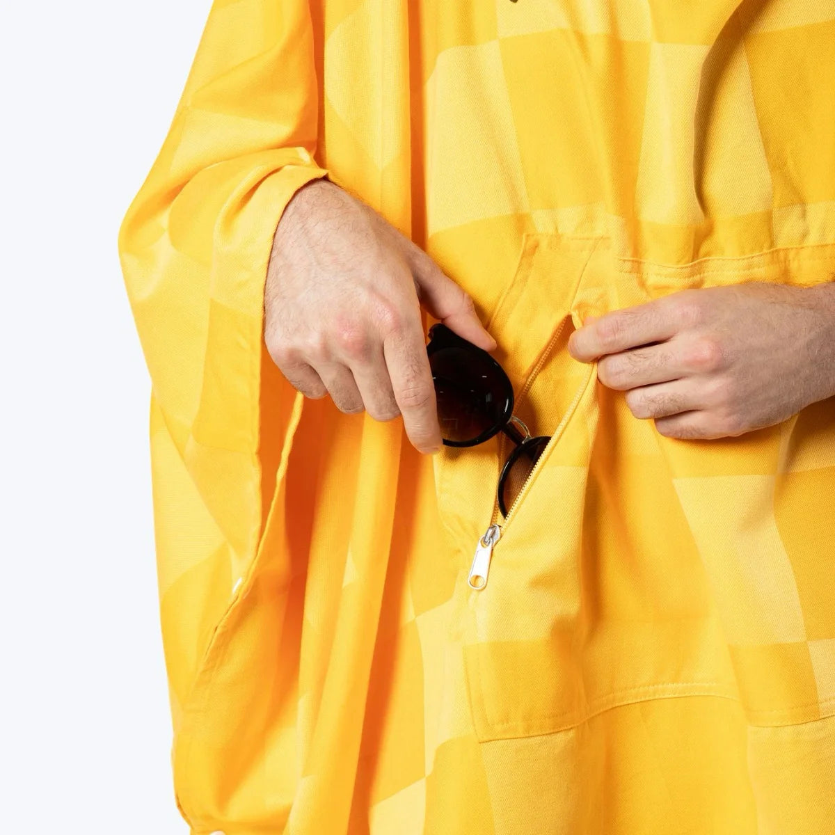 Golden yellow checkered oversized poncho with deep pockets, worn by person holding sunglasses