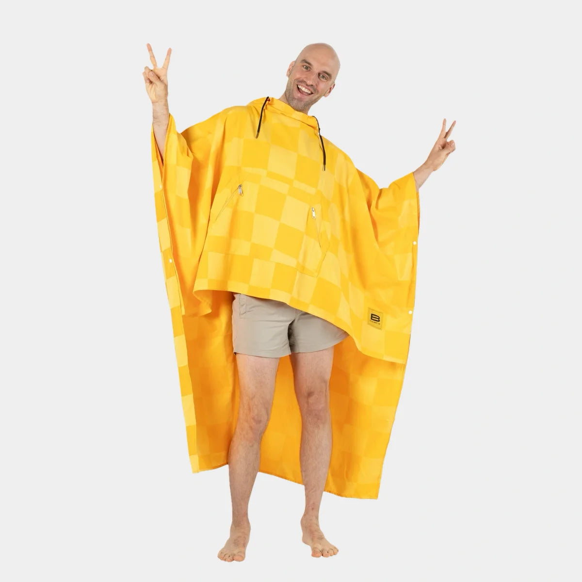 Man wearing golden yellow checkered oversized poncho blanket with arms outstretched