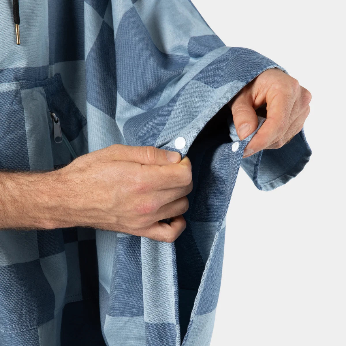 Adult wearing blue checkered poncho, hands demonstrating snap closure detail