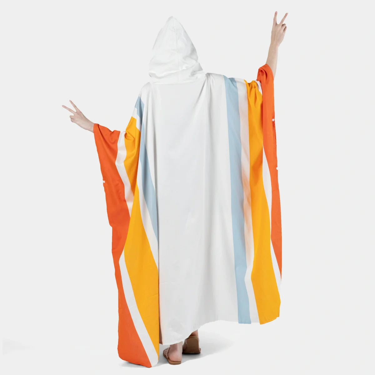 Person wearing oversized white hooded poncho blanket with orange, yellow, and blue vertical stripes, arms spread wide