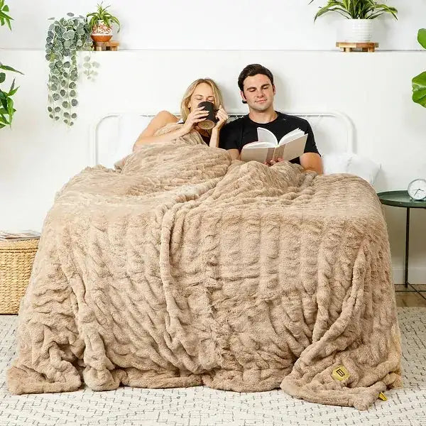 Couple on bed under oversized beige Cloud Luxe blanket with quilted texture pattern