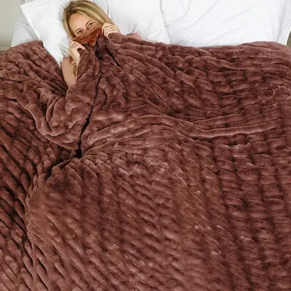 Woman wrapped in oversized mocha quilted blanket on bed, showing soft texture and generous coverage