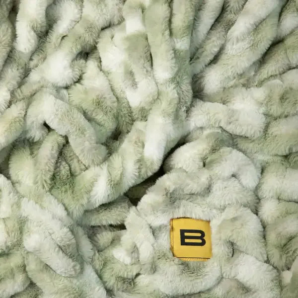 Cloud Luxe oversized blanket in sage green and cream, soft textured pile fabric with brand marker
