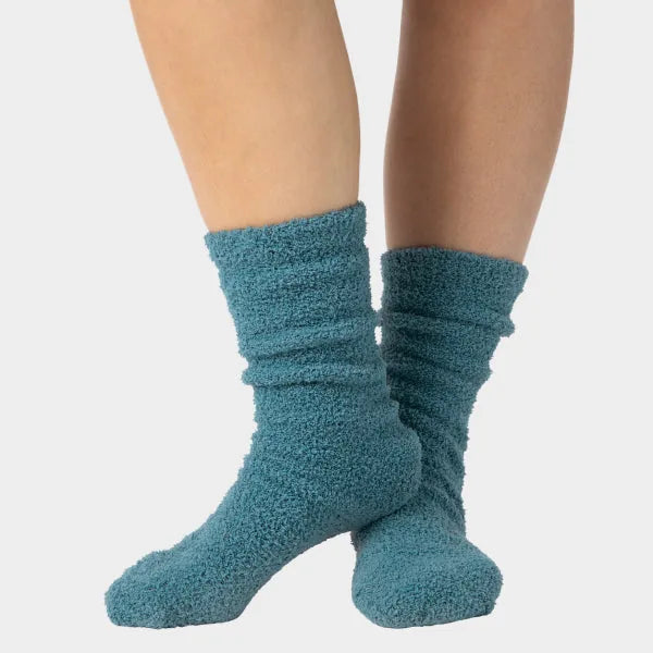 Teal cozy crew socks with textured knit fabric, bunched around ankles on model's feet