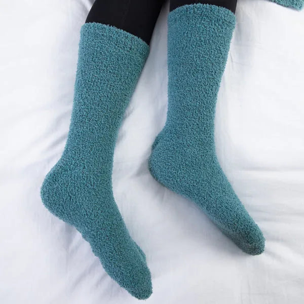 Teal cozy crew socks on white blanket background