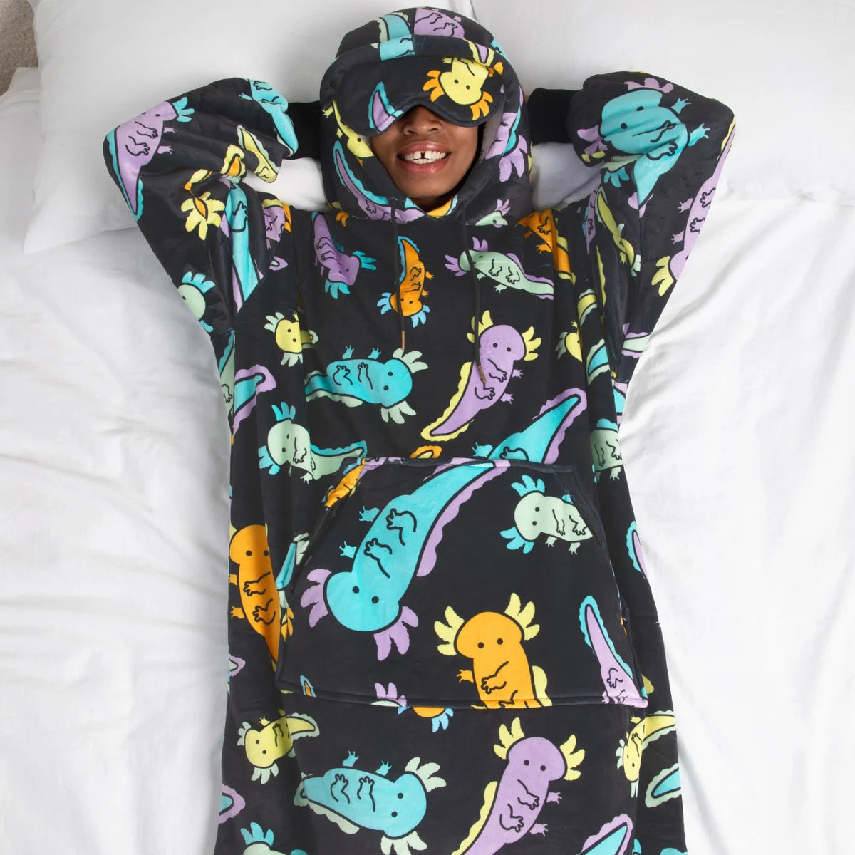 Person lying in bed in the Axolotl Drift Hideout Hoodie™ with the built-in eye mask pulled down