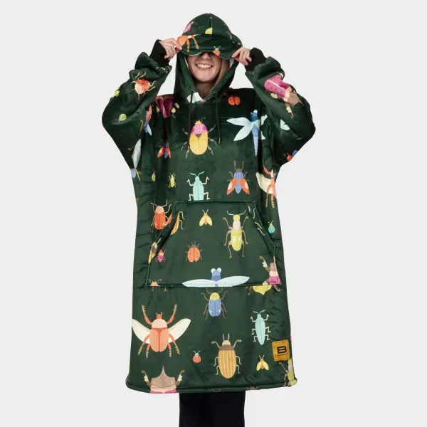 Forest green oversized hoodie blanket with colorful insect and bug print, worn by smiling person pulling hood up