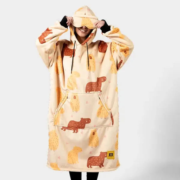Cream oversized hoodie blanket with brown and gold bear and animal print, kangaroo pocket, worn by person with hood up