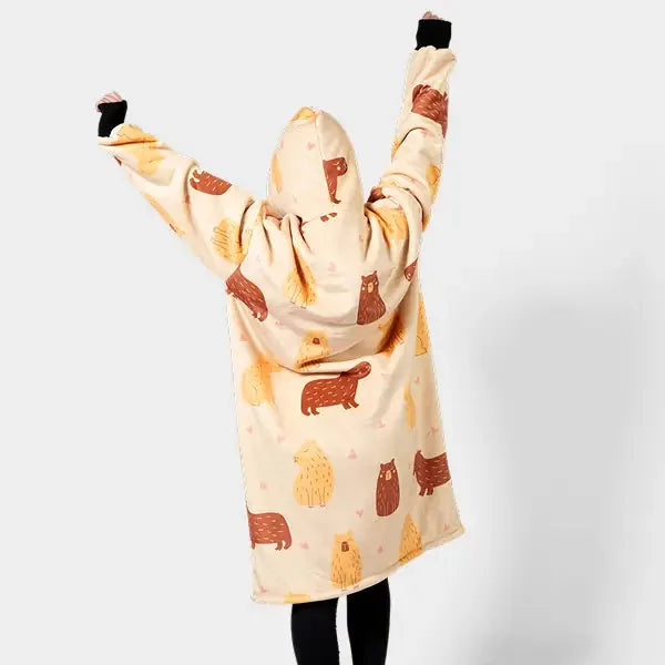 Cream wearable blanket with bear print, oversized hoodie design, person with arms raised wearing black socks