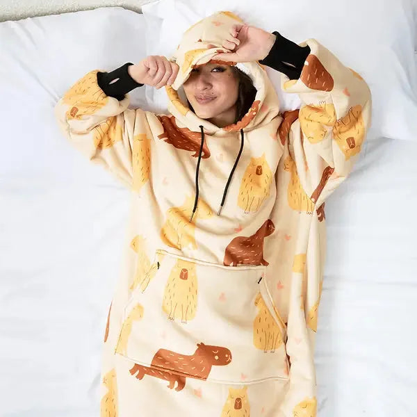 Child wrapped in cream Hideout Hoodie with brown dog and golden retriever print, pulling hood over head while lying on white bedding
