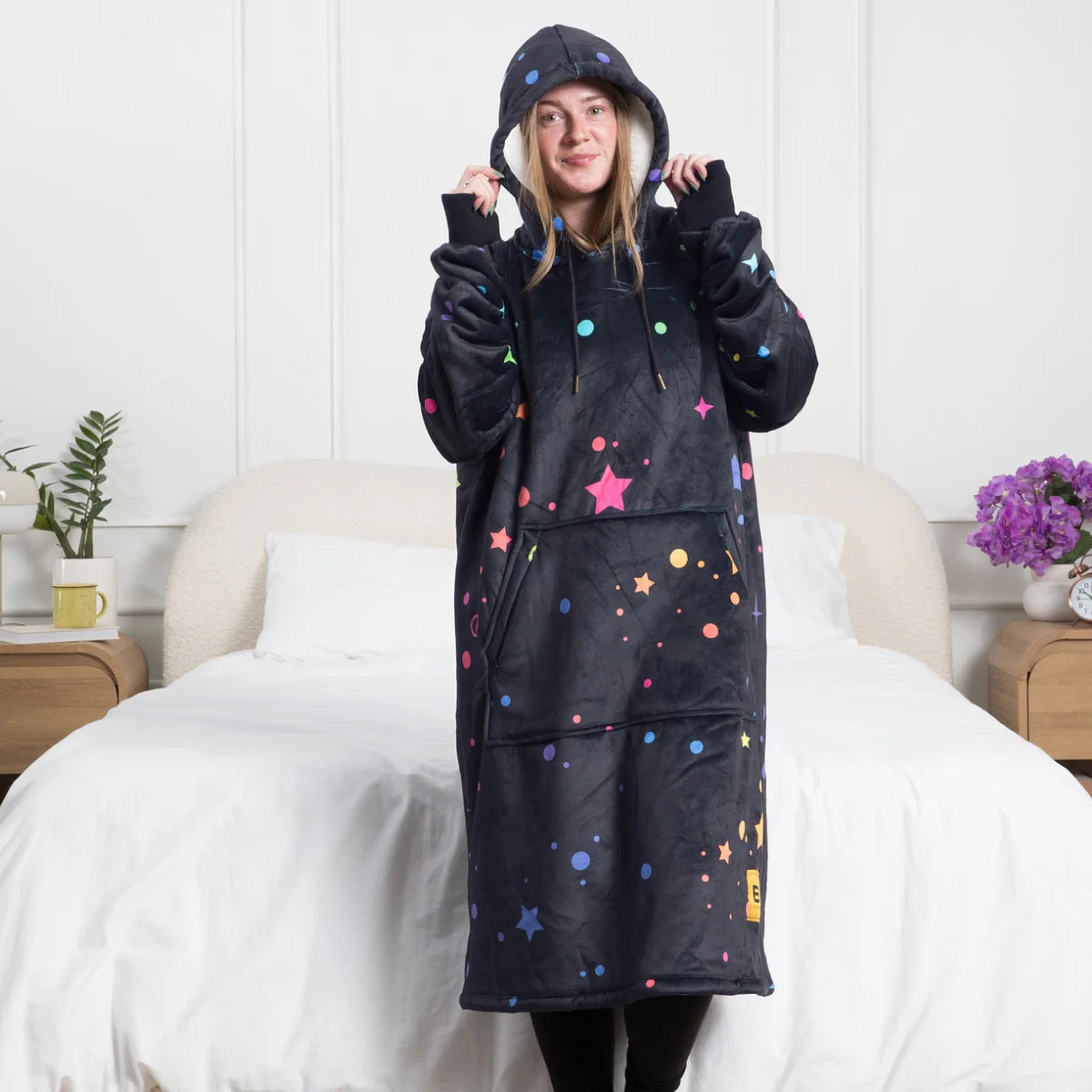 Person standing in a bedroom wearing the Electric Sky Hideout Hoodie™ with the hood up