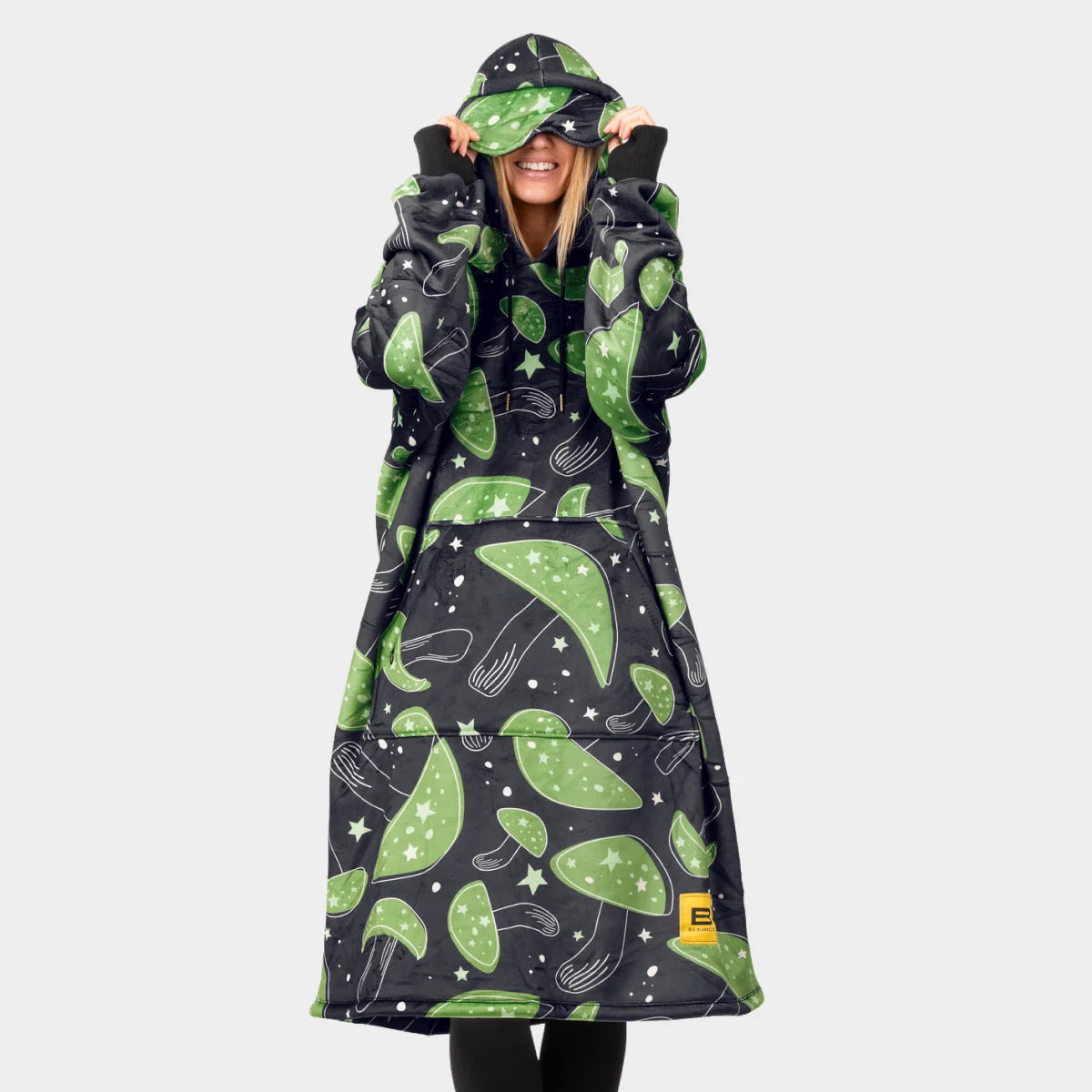 Person facing the camera pulling the built-in eye mask of the Mystic Mushrooms Hideout Hoodie™ down over their eyes