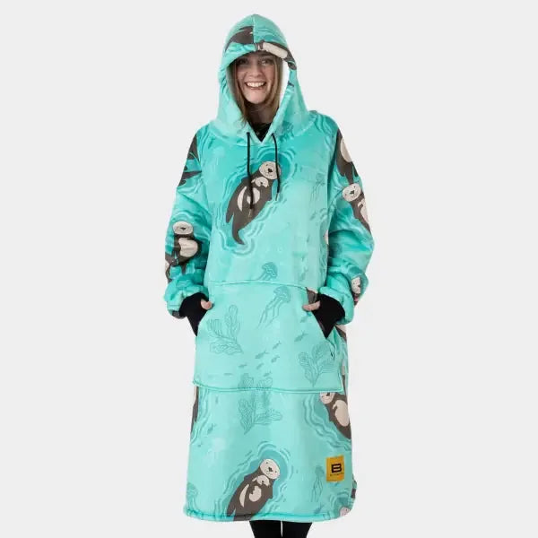 Turquoise Hideout Hoodie wearable blanket with otter print, hood and front pocket, modeled by smiling woman