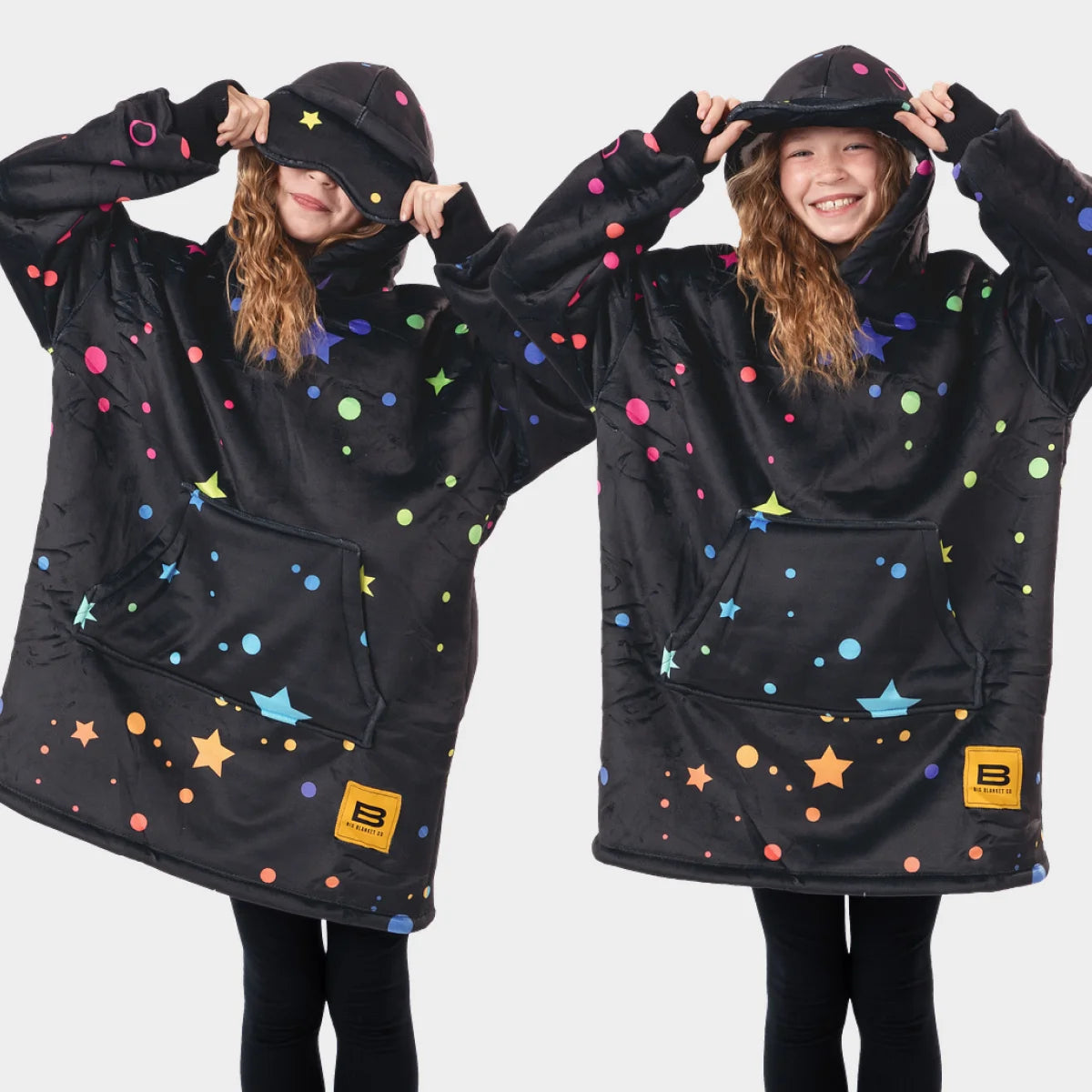 Two children side by side wearing the Electric Sky Hideout Hoodie™ Kids, lifting the built-in eye masks off their eyes
