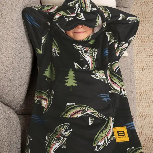 Child wrapped in black oversized blanket with fishing and forest print, face covered playfully with blanket edge