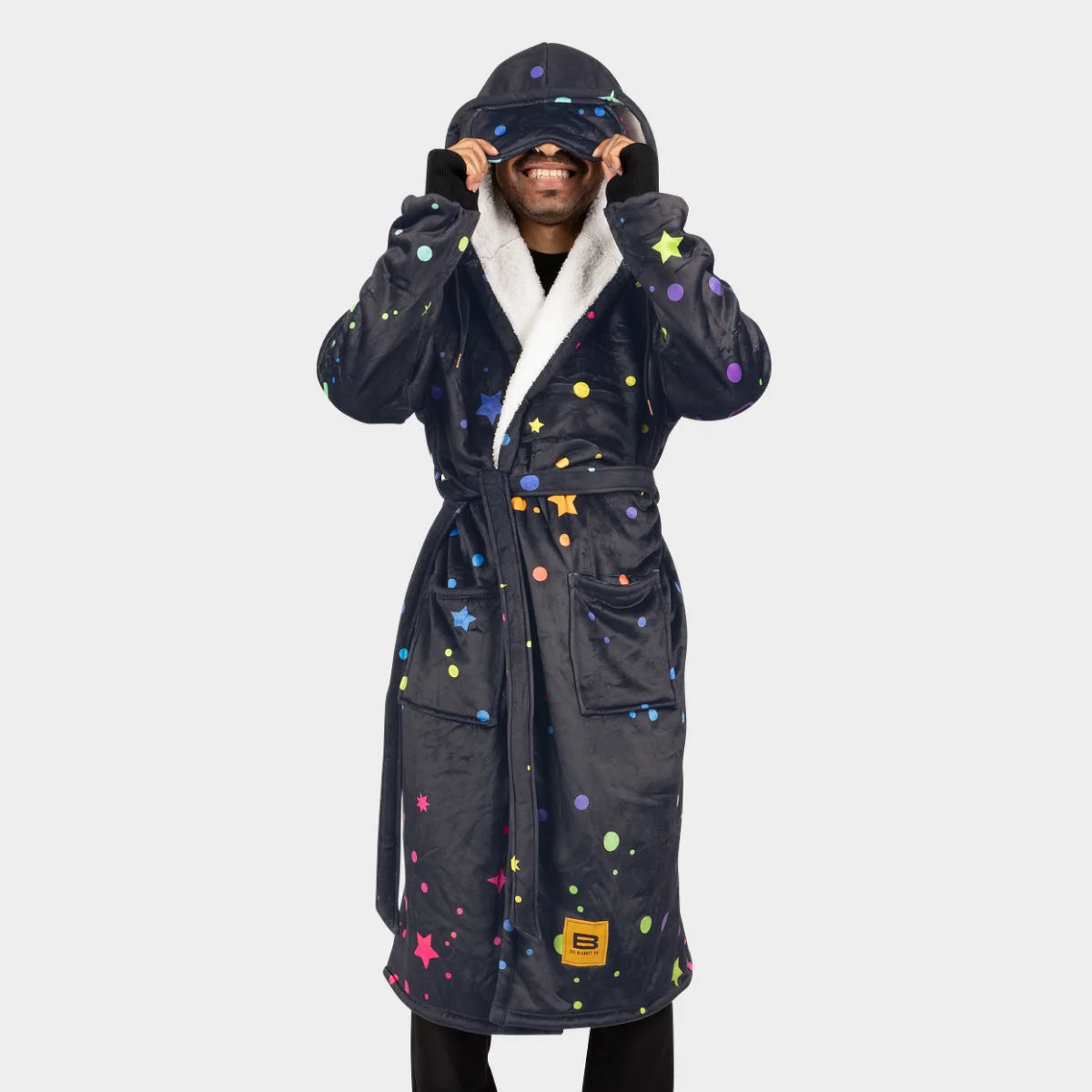Person wearing the Electric Sky Hideout Robe™ and lifting the built-in eye mask, sherpa-lined hood and lapel visible