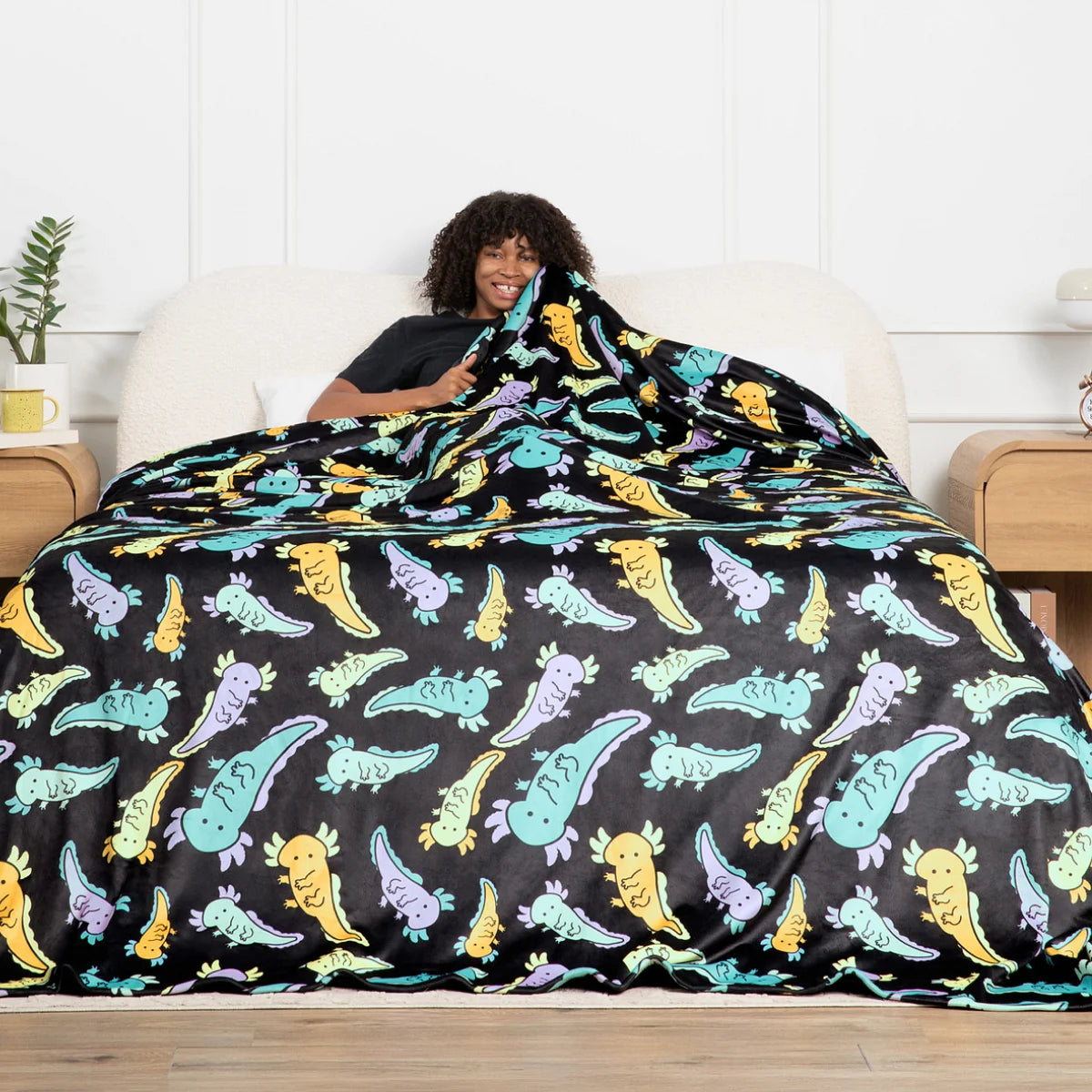 Person sitting up in bed wrapped in the Axolotl Drift Original Stretch™ oversized blanket