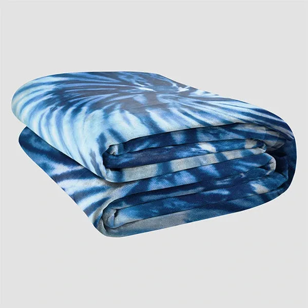 Blue tie-dye oversized blanket rolled and folded, showing soft texture and light-to-dark blue gradient pattern