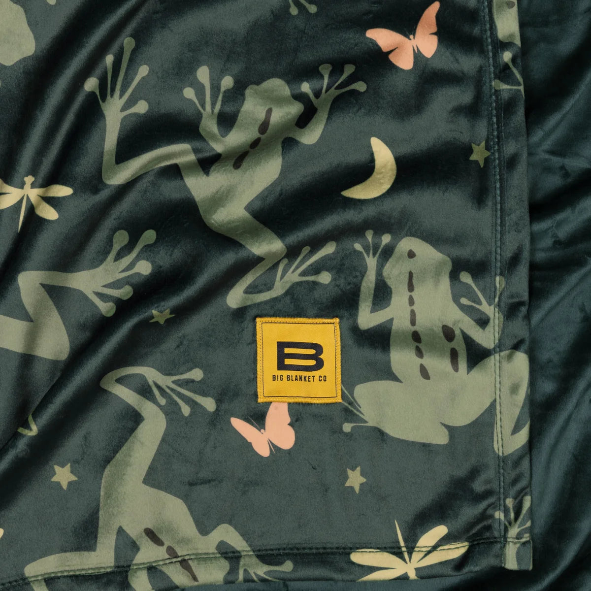 Close-up of the Dreamy Frogs Original Stretch™ blanket showing the print and the yellow Big Blanket Co label