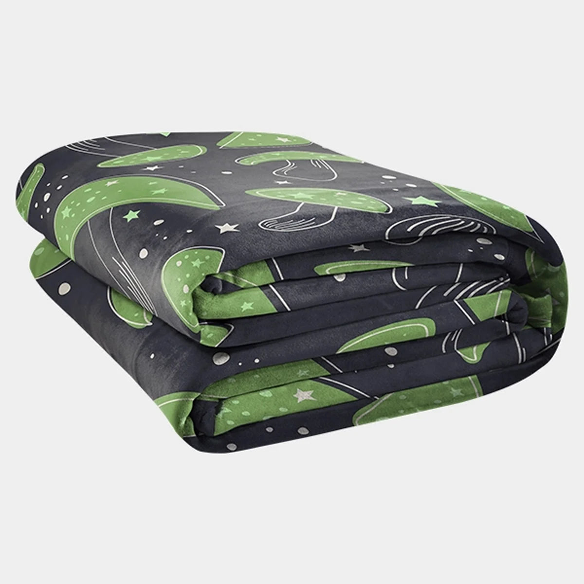 Original Stretch™ oversized blanket in Mystic Mushrooms, folded into a stack — near-black charcoal ground scattered with large green mushroom caps, cream stars and speckles