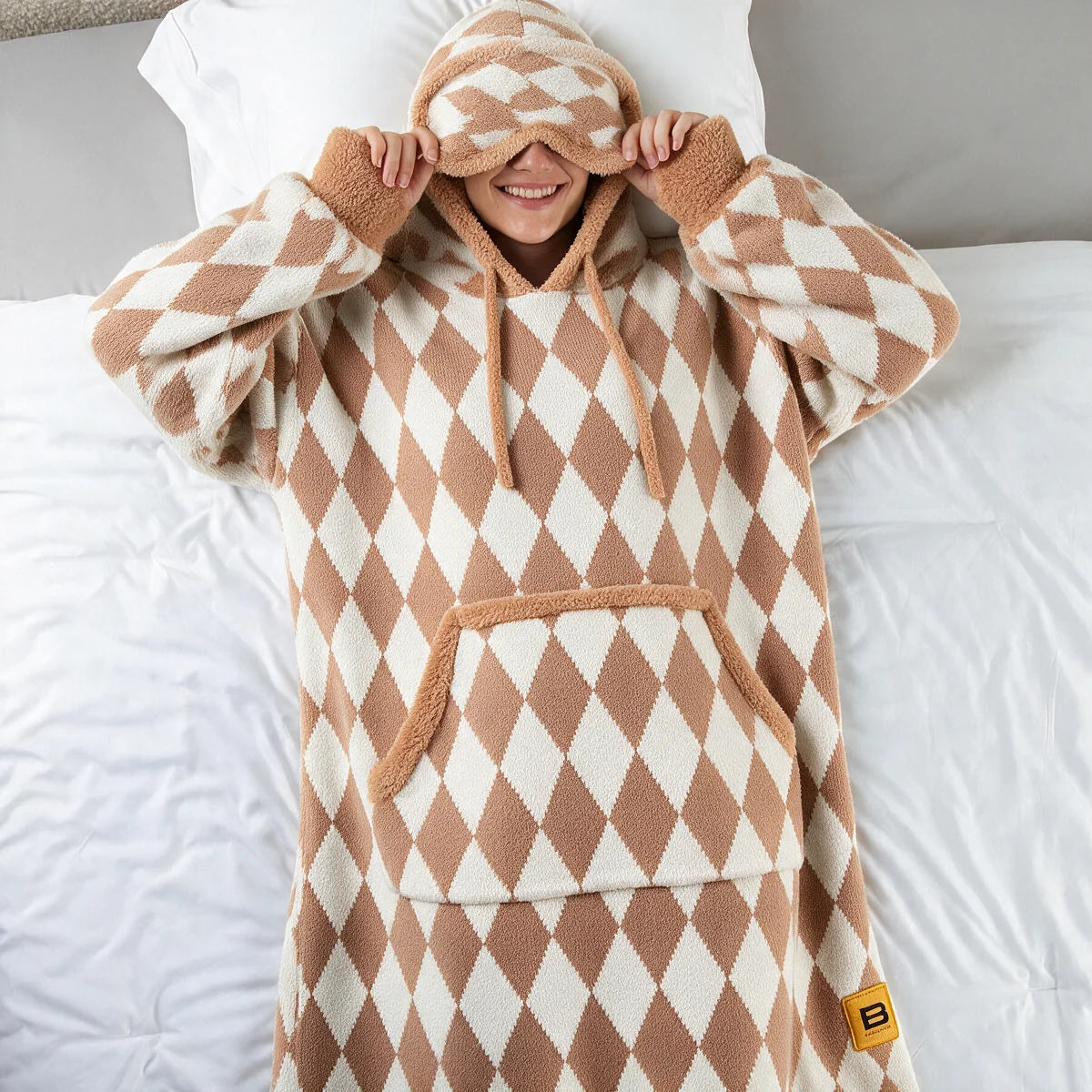 Person lying back on white bedding in the Dusty Diamond Premier Plush™ Hoodie with the built-in eye mask pulled down