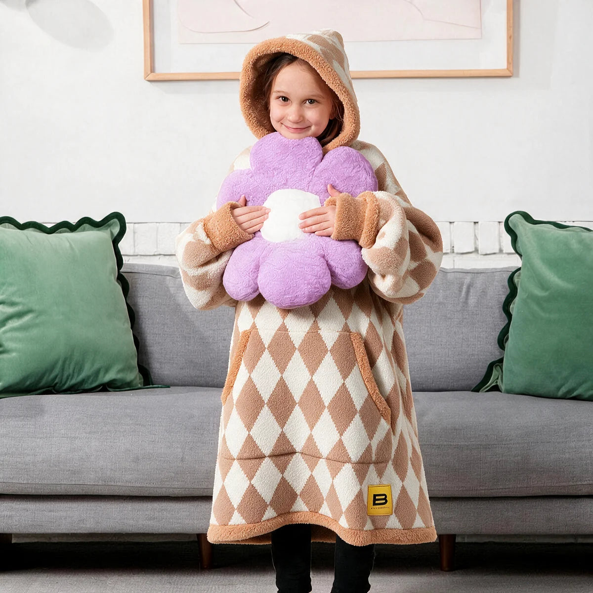 Child standing in front of a couch wearing the Dusty Diamond Premier Plush™ Hoodie Kids with the hood up