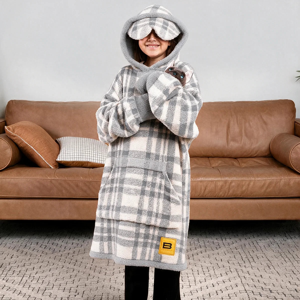 Child resting against a cushion wearing the Grey Plaid Premier Plush™ Hoodie Kids