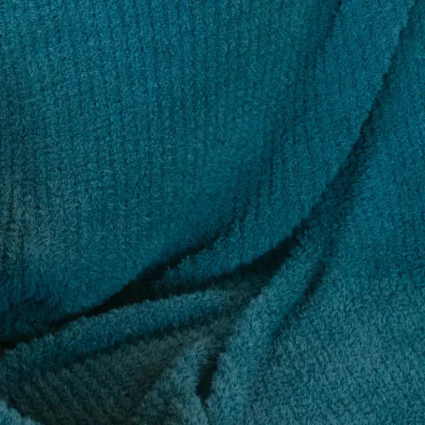 Teal oversized blanket with soft plush texture and gathered folds showing material depth