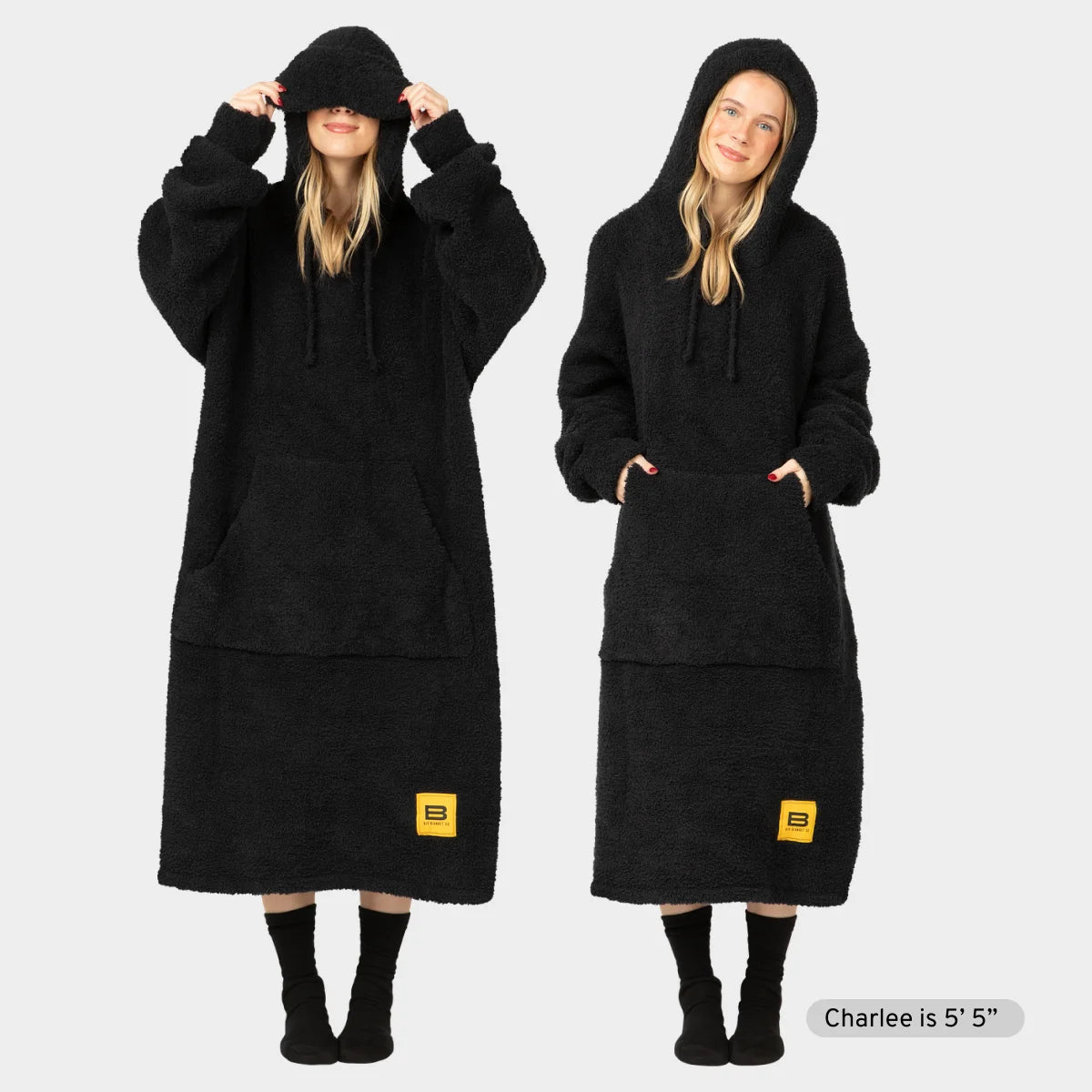 Black oversized hoodie blanket with drawstring hood, kangaroo pocket, and Big Blanket Co logo, shown two ways on model