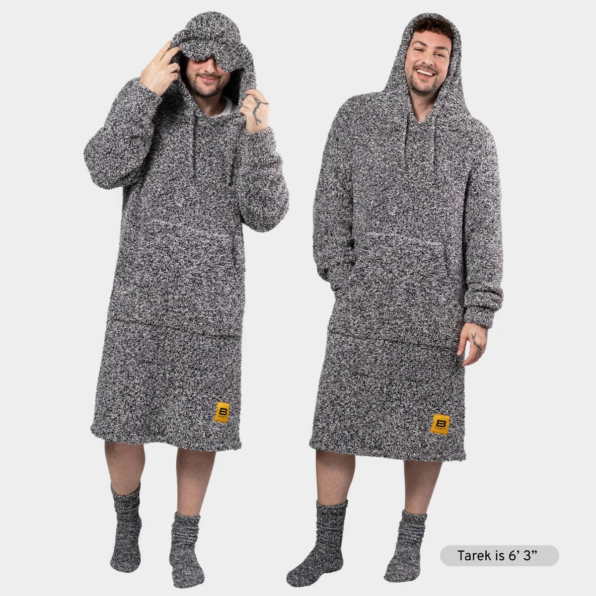 Two men wearing charcoal heather oversized hoodie blankets with matching socks, demonstrating full-length fit and hood coverage