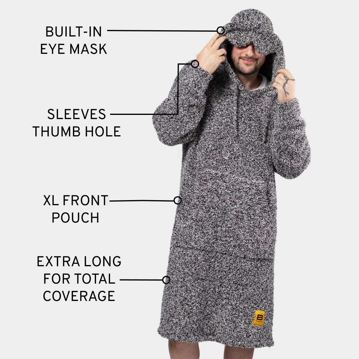 Man wearing gray heather hoodie blanket with built-in eye mask, thumb hole sleeves, and extra-long coverage