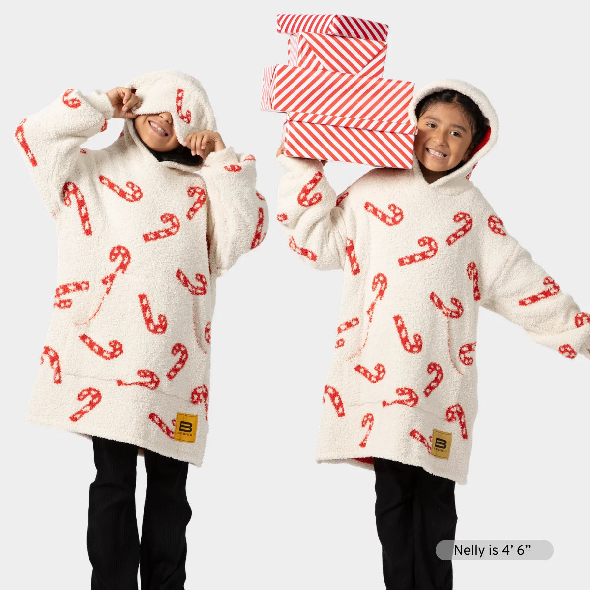 Cream Premier Plush hoodie blanket with red candy cane pattern, shown front and back on model wearing matching socks