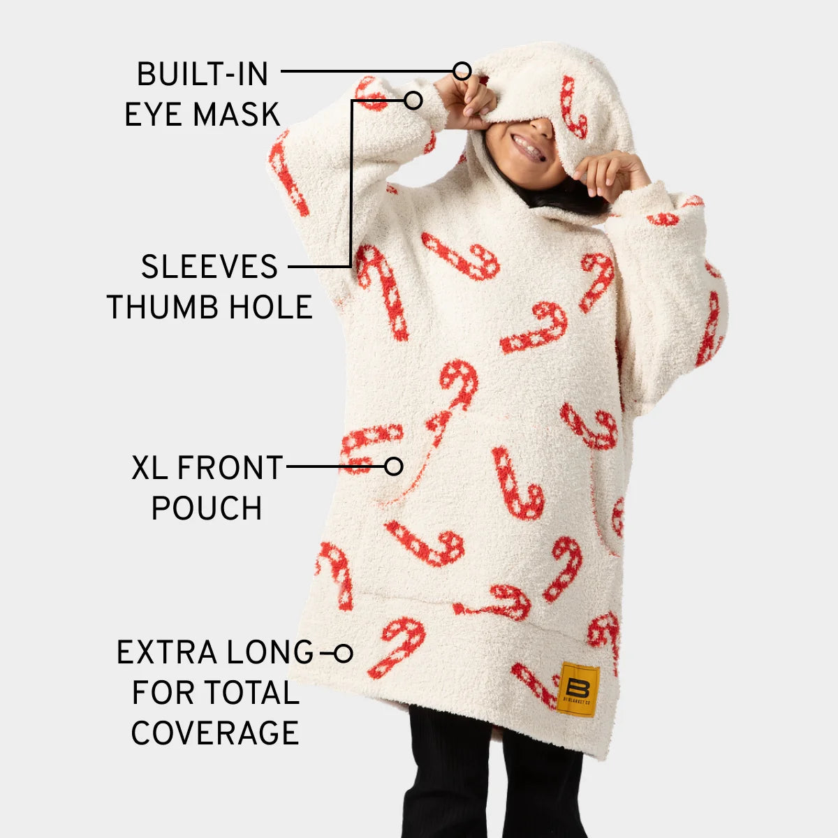 Cream oversized hoodie blanket with red candy cane pattern, featuring built-in eye mask, thumb holes, and XL front pouch