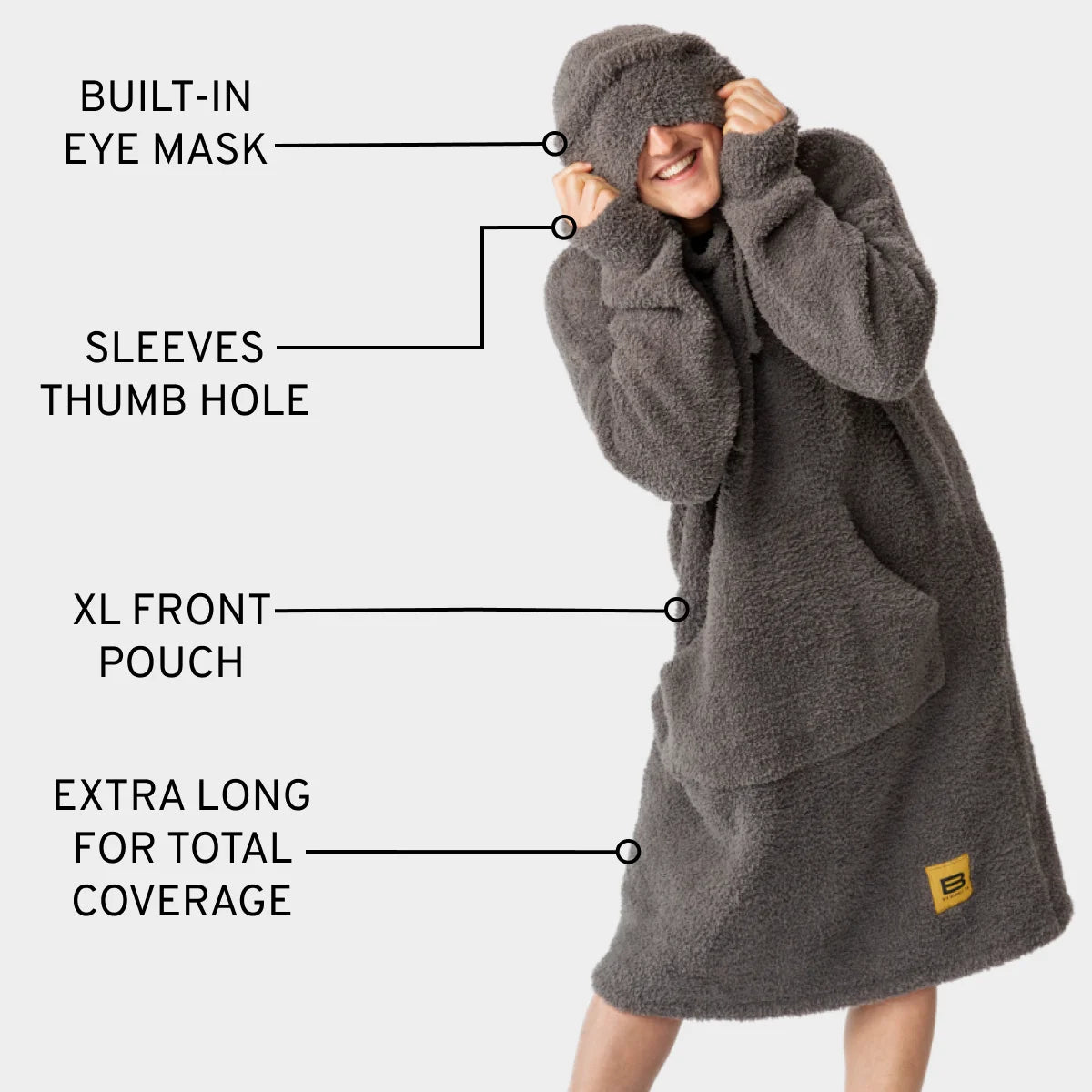 Woman wearing charcoal oversized blanket hoodie with built-in eye mask, thumb hole sleeves, and XL front pouch