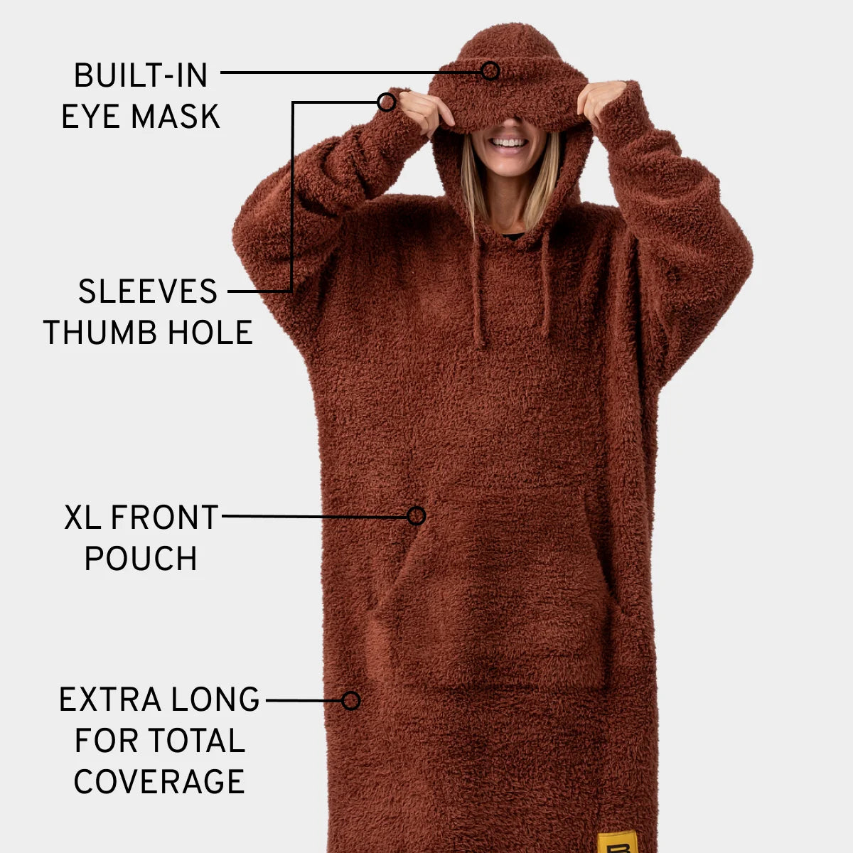 Woman wearing chocolate brown oversized blanket hoodie with built-in eye mask, thumb hole sleeves, and XL front pouch