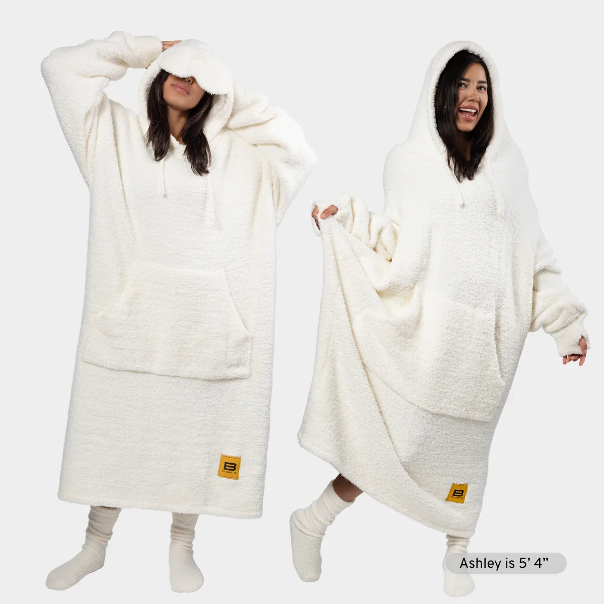 Women wearing cream Premier Plush hoodie blanket with oversized hood, front pocket, and sleeves in two styling positions