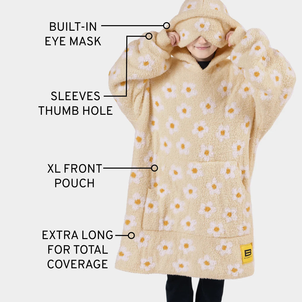 Cream oversized hoodie blanket with yellow daisy print, featuring built-in eye mask, thumb holes, front pouch, and extra-long length for kids