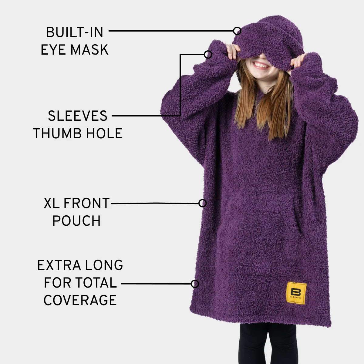 Deep purple oversized hoodie blanket with built-in eye mask, thumb holes, and XL front pouch on child model