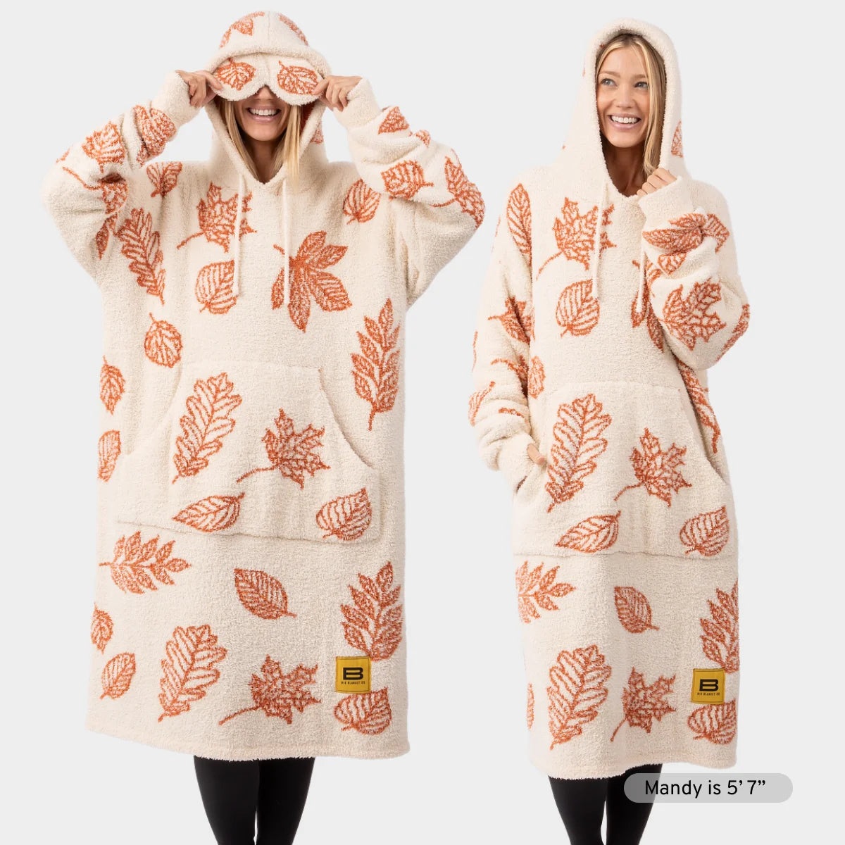 Cream oversized hoodie blanket with rust orange falling leaves pattern, modeled by two women wearing matching hoodies with hoods up