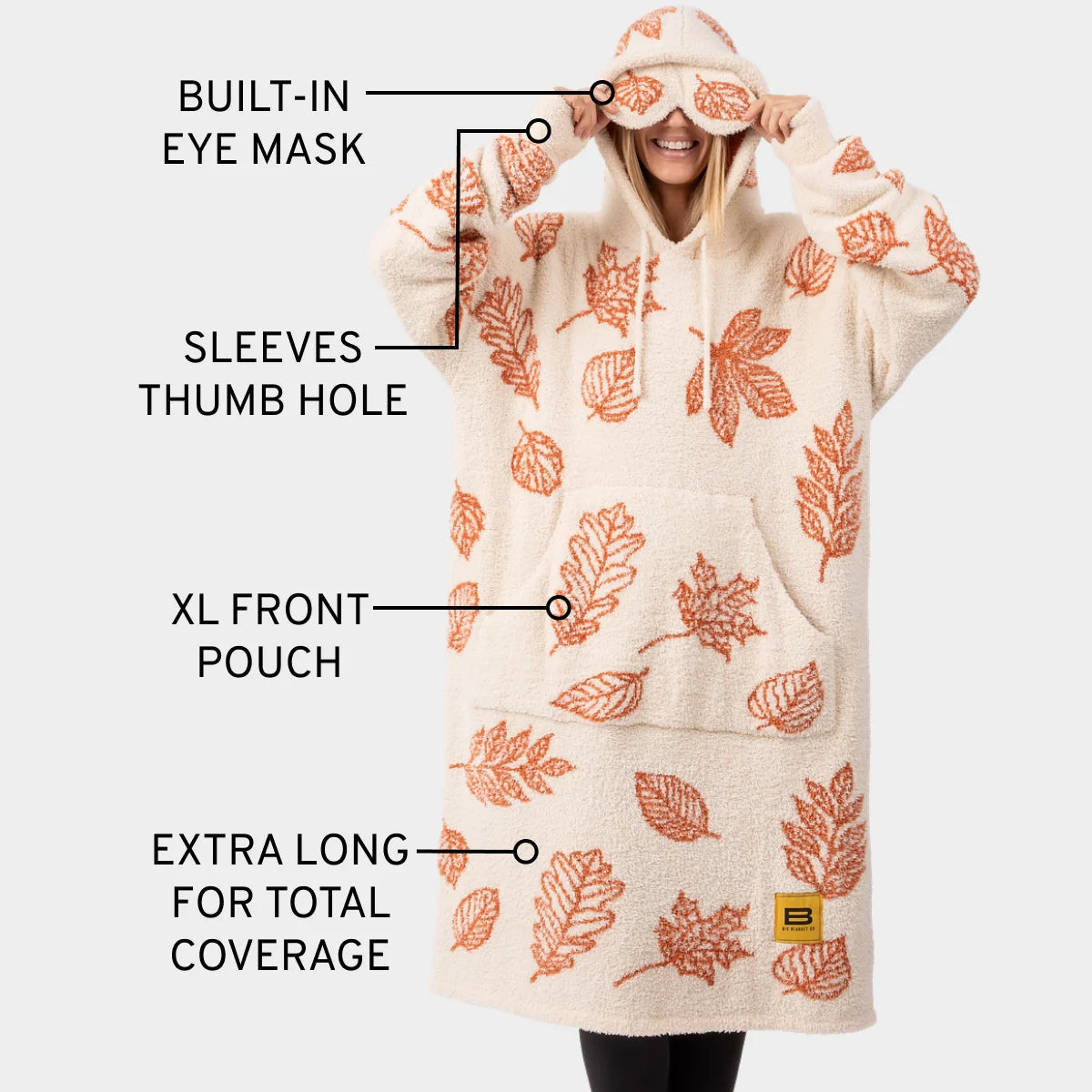 Cream oversized hoodie blanket with rust leaf print, built-in eye mask, thumb holes, front pouch, extra length coverage
