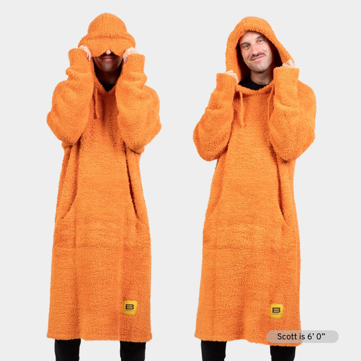 Orange oversized hoodie blanket with plush texture, hood and kangaroo pocket, shown on two models demonstrating fit and styling options