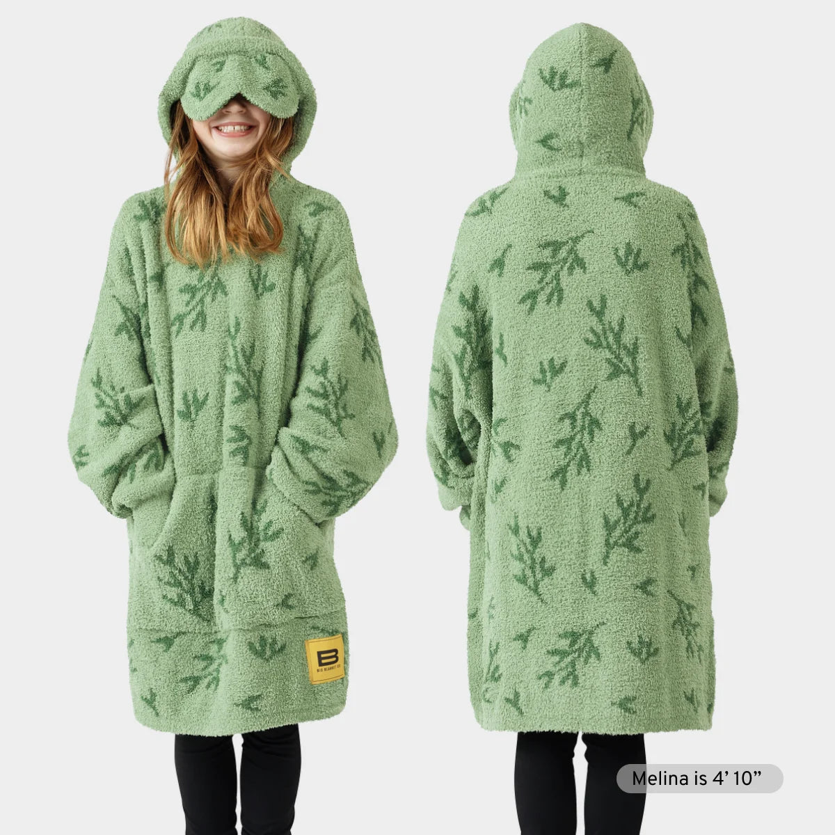 Green oversized hoodie blanket with leaf pattern, front and back view, worn by person with matching hood covering face
